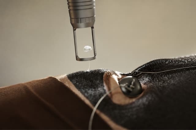 Close-up of a Carbon Laser Facial — also known as the Hollywood Peel — at The Wellness Ed. A precision laser handpiece is held just above a guest's cheek that has been coated in a fine layer of black carbon mask, with a small protective metal eye shield in view and the warm, low-lit treatment room reflecting the calm, doctor-led technique.