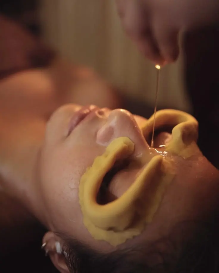 Guest receiving Netra Dhara at The Wellness Ed — warm medicated ghee gently poured into dough wells around closed eyes for deep ocular relaxation.