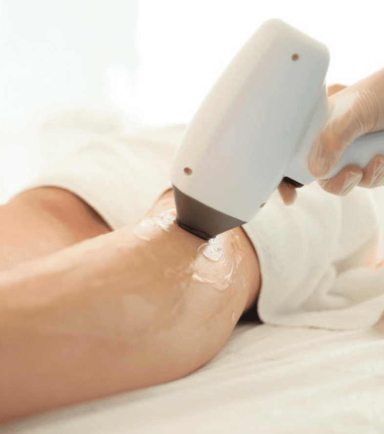 Cool-tip diode laser handpiece gliding over cooling gel on a guest's leg during a Laser Hair Reduction session at The Wellness Ed.