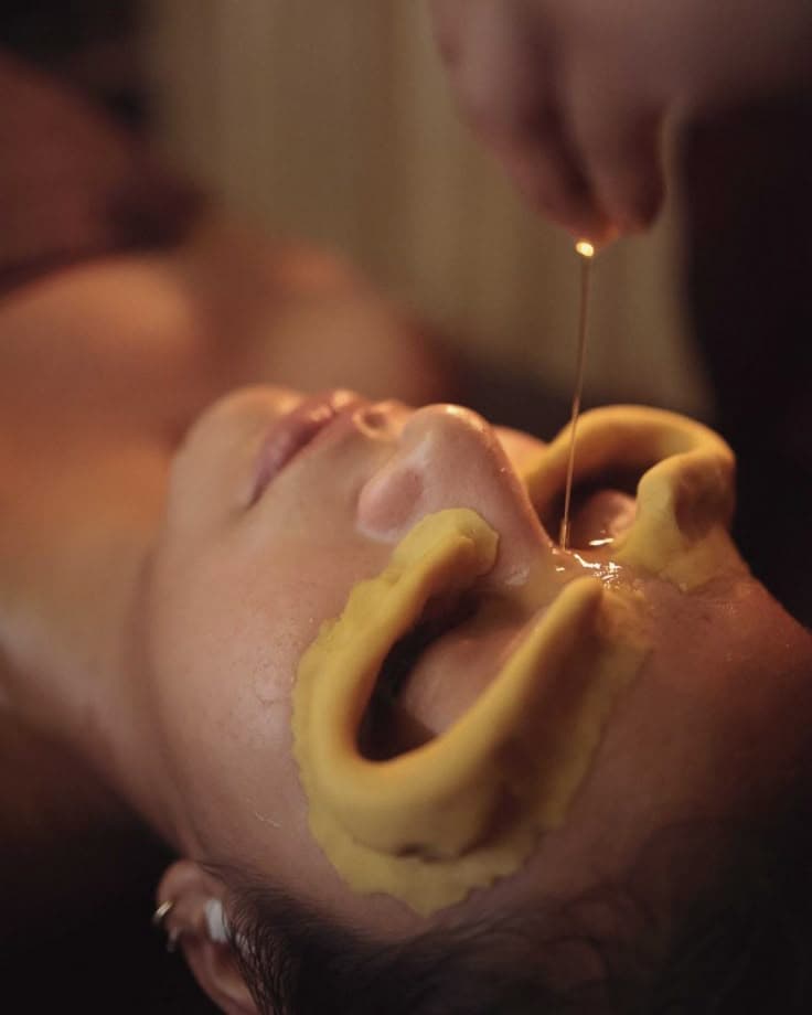 Guest receiving Netra Dhara at The Wellness Ed — warm medicated ghee gently poured into dough wells around closed eyes for deep ocular relaxation.