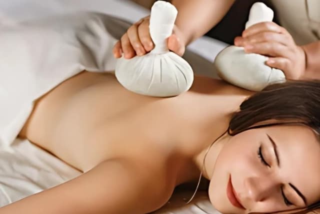 A guest relaxing during a slimming-focus Potli Therapy at The Wellness Ed — a therapist rhythmically presses warm, herb-filled cotton potlis along the shoulders and upper back to support circulation and fat breakdown.