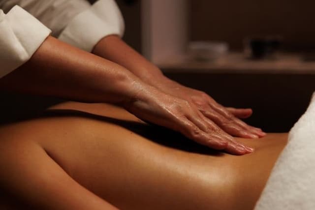 Therapist applying warm herbal oil with gentle, rhythmic strokes during a restorative Ayurvedic massage at The Wellness Ed.