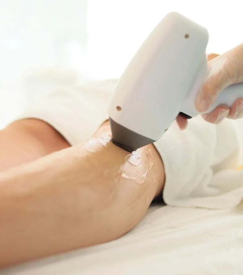 Cool-tip diode laser handpiece gliding over cooling gel on a guest's leg during a Laser Hair Reduction session at The Wellness Ed.